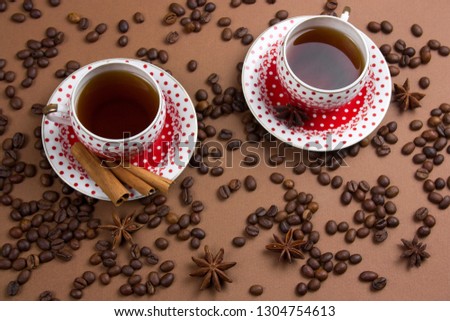 two spicy black coffee polka dot mugs and coffee beans mess on brown  background