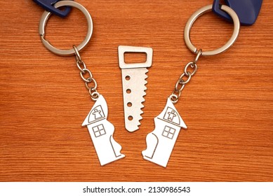 Two Split House Matching Keychains With A Small Steel Saw On A Wooden Table. Splitting Assets In A Divorce.