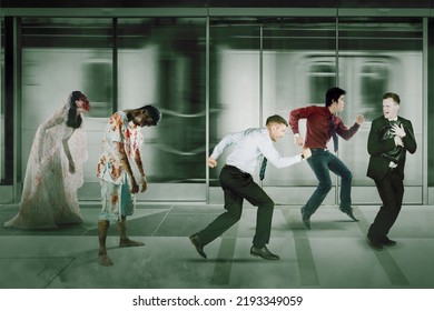 Two Spooky Zombies Chasing A Group Of Businessman While Running In The Train Station