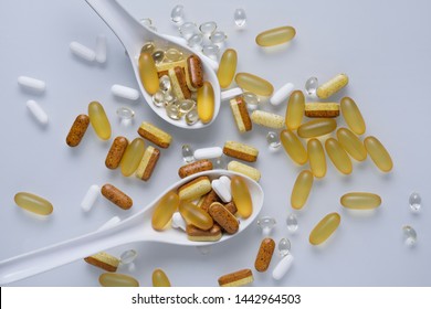Two spoons full of pills and capsules on white background.  Medical concept. 