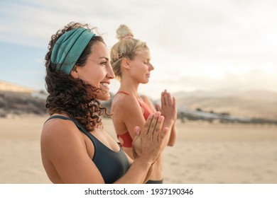 Two Sportive Women Meditating And Doing Yoga At The Beach - Beautiful Girl Wearing Activewear - Women Meditating In The Desert