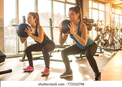 Two sporty girls doing exercises with fitness balls in the gym.