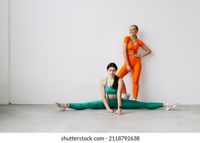 Two Sporty Women Doing Side Leg Raise Exercise With Stretch Band Lying On Floor