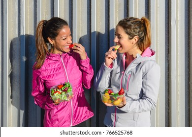 Two Sporty Women On Fitness Diet Eating A Healthy Green Salad With Fruits After Exercising.