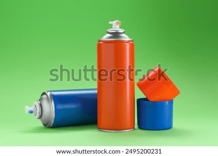 Two spray paint cans on green background
