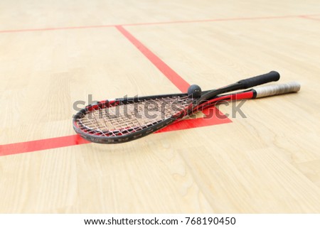 two squash rackets and ball on the wooden floor. Racquetball equipment on the court on red lines. Photo with selective focus