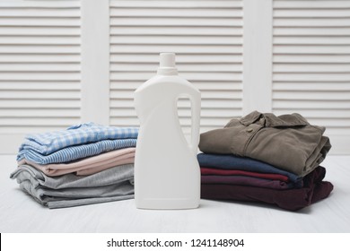 Two Stack Of Folded Clothes And Detergent Bottle. Dark And Light Linen