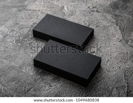 Two stacks of black blank business cards on wooden background.
