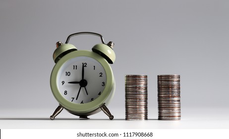 Two stacks of coins of the same height as an alarm clock.