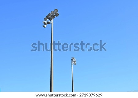 Two stadium light clusters against a blue sky