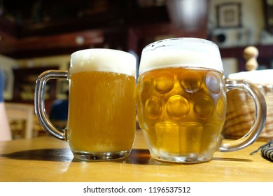 Two steamed mugs with light foam beer in the pub
