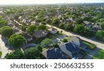 Two story suburban houses in West Plano, Texas with city water tower, downtown buildings skylines background, upscale neighborhood tree lined street in Wentworth Estates, suburbs Dallas, aerial. USA