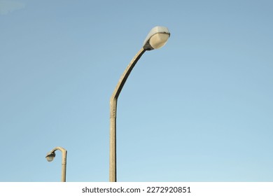 Two street light lamp posts against a clear, pure blue sky. Minimalist photo, copy space. Taken at the A666, England, UK. Pastel color, abstract, conceptual stock photo. Copy space, clean background
