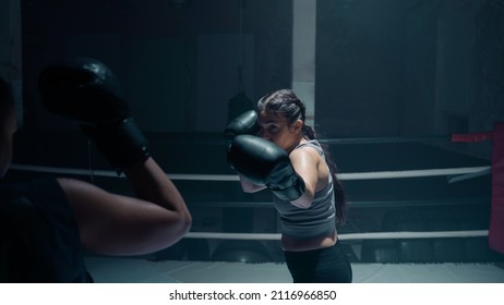 Two Strong and Athletic Female Boxers Sparring in a Boxing Ring. Caucasian Confident Looking Woman Wearing Gloves and Guards As She Protects Herself From a Hit, Athletic Fitness Martial Arts Concept.