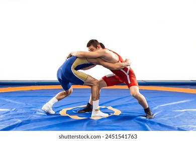 Two  strong men in blue and red wrestling tights are wrestling  on a white background. Wrestlers doing grapple. 