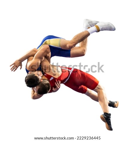 Two  strong men in blue and red wrestling tights are wrestling and making a suplex wrestling on a white background. Wrestlers doing grapple. 