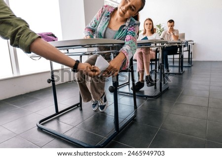 Two students cheating in class for their exam. Passing the note under the table