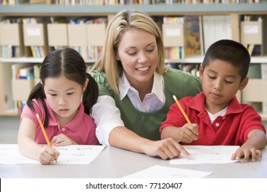 Two students in class writing with teacher helping