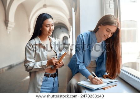 Two students collaborate on coursework, building a friendship in a university hallway, focusing on learning and teamwork. Their collaboration symbolizes the significance of education and teamwork