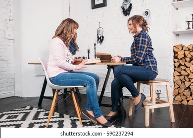 Two students doing homework together and helping each other sitting in a table at home with a homey background
