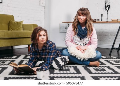 Two students doing homework together and helping each other lying on the floor at home with a homey background