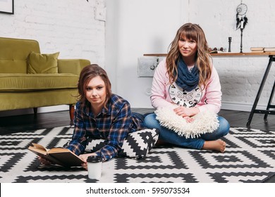 Two students doing homework together and helping each other lying on the floor at home with a homey background