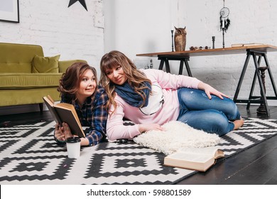 Two students doing homework together and helping each other lying on the floor at home with a homey background