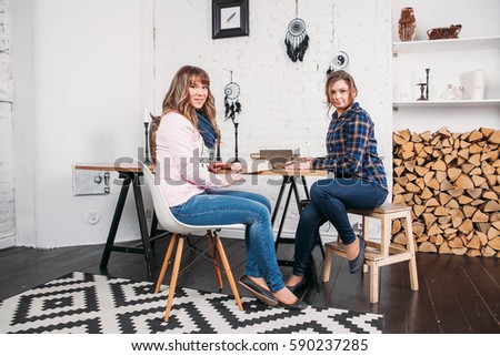 Two students doing homework together and helping each other sitting in a table at home with a homey background