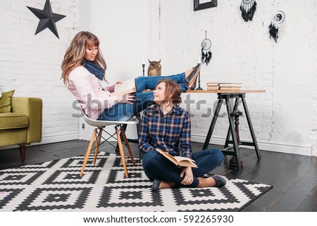 Two students doing homework together and helping each other sitting in a table at home with a homey background