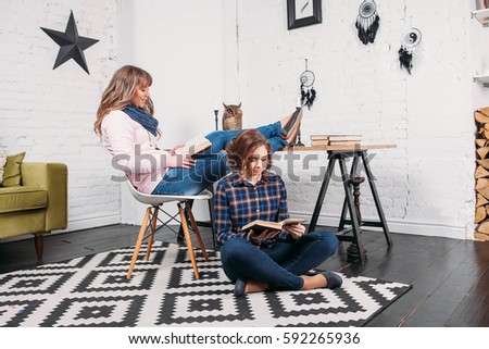 Two students doing homework together and helping each other sitting in a table at home with a homey background
