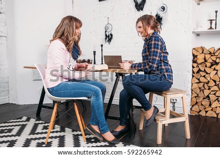 Two students doing homework together and helping each other sitting in a table at home with a homey background