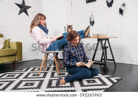 Two students doing homework together and helping each other sitting in a table at home with a homey background