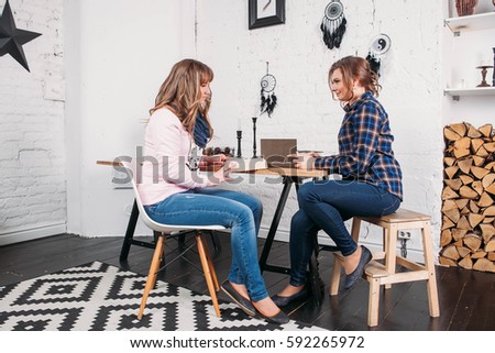 Two students doing homework together and helping each other sitting in a table at home with a homey background