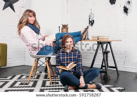 Two students doing homework together and helping each other sitting in a table at home with a homey background