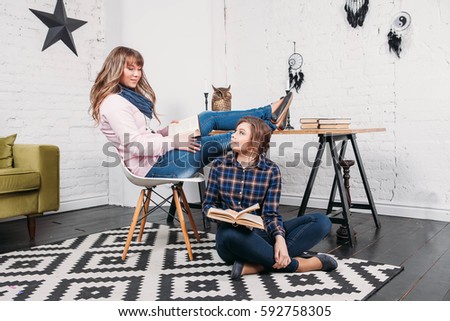 Two students doing homework together and helping each other sitting in a table at home with a homey background