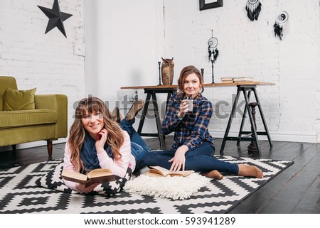 Two students doing homework together and helping each other sitting in a table at home with a homey background