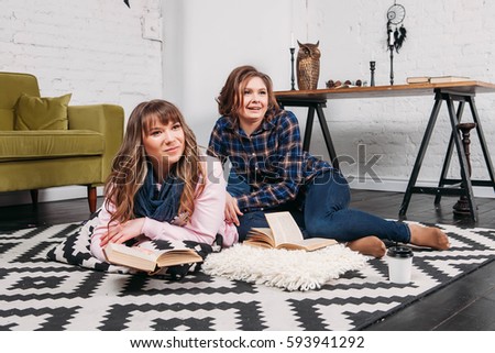 Two students doing homework together and helping each other sitting in a table at home with a homey background