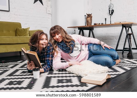 Two students doing homework together and helping each other lying on the floor at home with a homey background