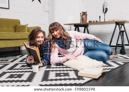 Two students doing homework together and helping each other lying on the floor at home with a homey background