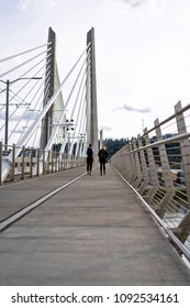 Two Students Girls With Backpacks Walking On Pedestrian Part Of Transportation Tilikum Crossing Bridge With Railway For Streetcar Across The Willamette River In Portland Oregon