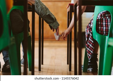 Two Students Hands Passing Notes To Each Other Secretly During Class. Young Students Cheating On An Exam.