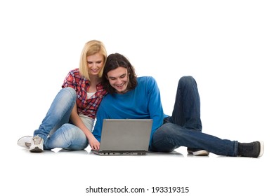 Two students with laptop. Smiling girl and boy sitting on the floor and using laptop. Full length studio shot isolated on white. - Shutterstock ID 193319315