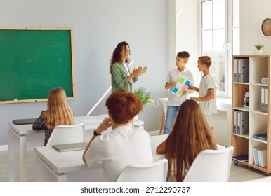 Two students presenting a project or classwork during a lesson with the teacher in a school classroom. This activity highlights studying, learning, and teamwork in educational environment.