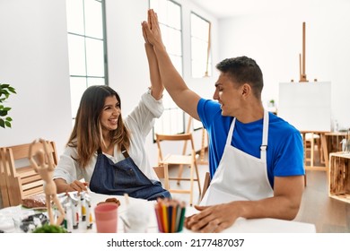 Two Students Smiling Happy Modeling Clay And High Five At Art School.