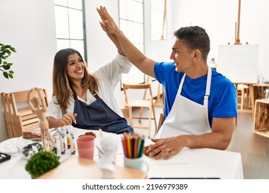 Two Students Smiling Happy Modeling Clay And High Five At Art School.