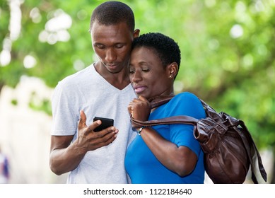 two students standing in park and look at mobile phone while smiling. - Shutterstock ID 1122184640