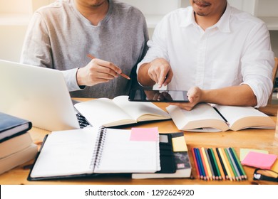 Two students studying and learning in library with a laptop and notes. - Shutterstock ID 1292624920