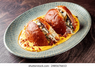 Two stuffed buns with creamy sauce, garnished with herbs, served on a blue plate - Powered by Shutterstock