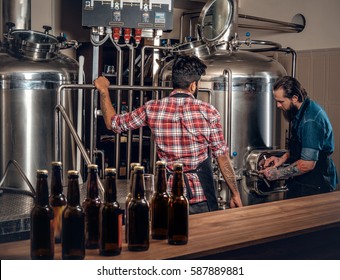 Two Stylish Bearded Men Brewing Beer In The Craft Microbrewery.