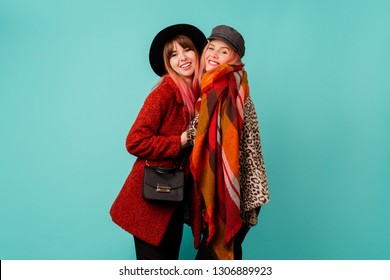 Two Stylish Blond  Women Posing In Studio On Blue Turquoise Background. Friends Hugging And Having Fun Together.  Wearing Leopard Print Faux Fur Coat And Wool Scarf. Winter Fashion.